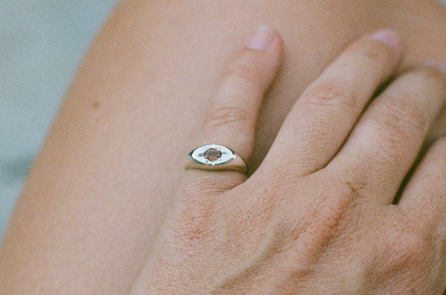 Hand with a ring on a blurred natural background