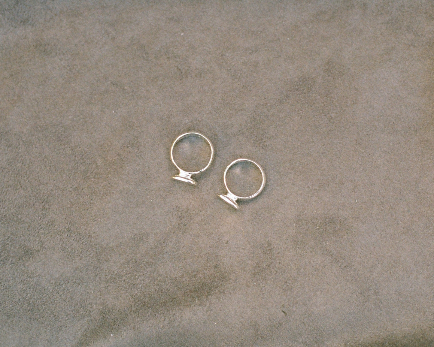 Pair of silver rings on a textured beige surface
