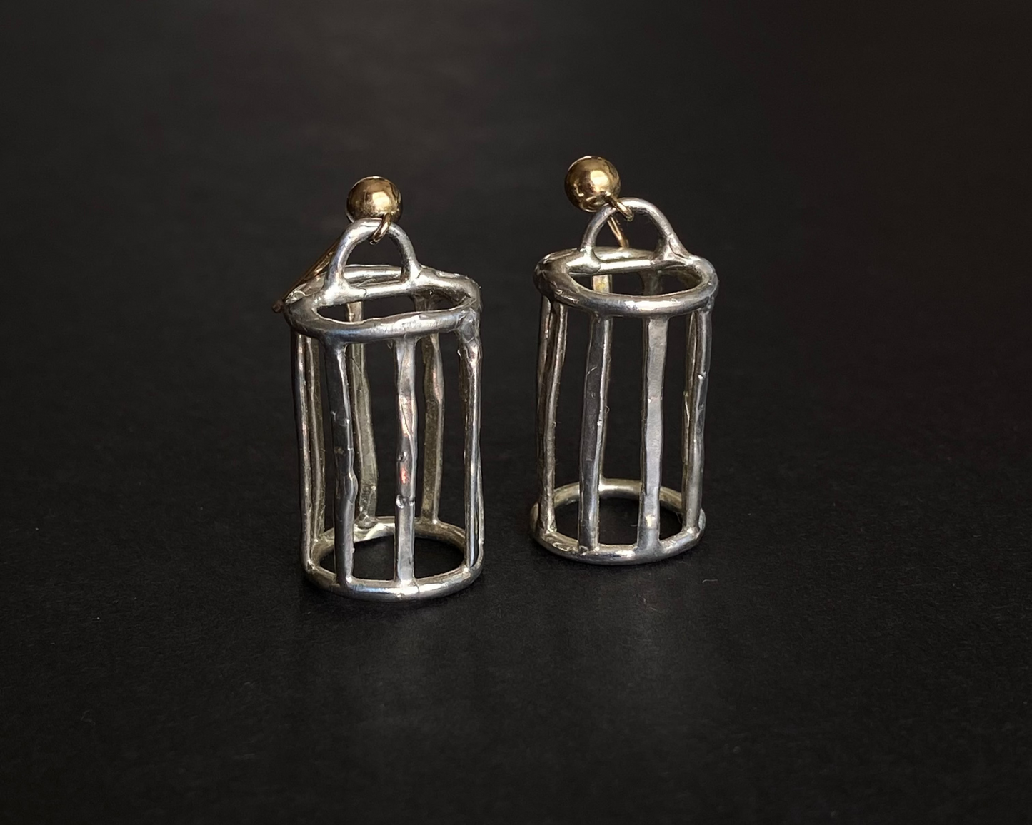 Silver cage earrings on a black surface