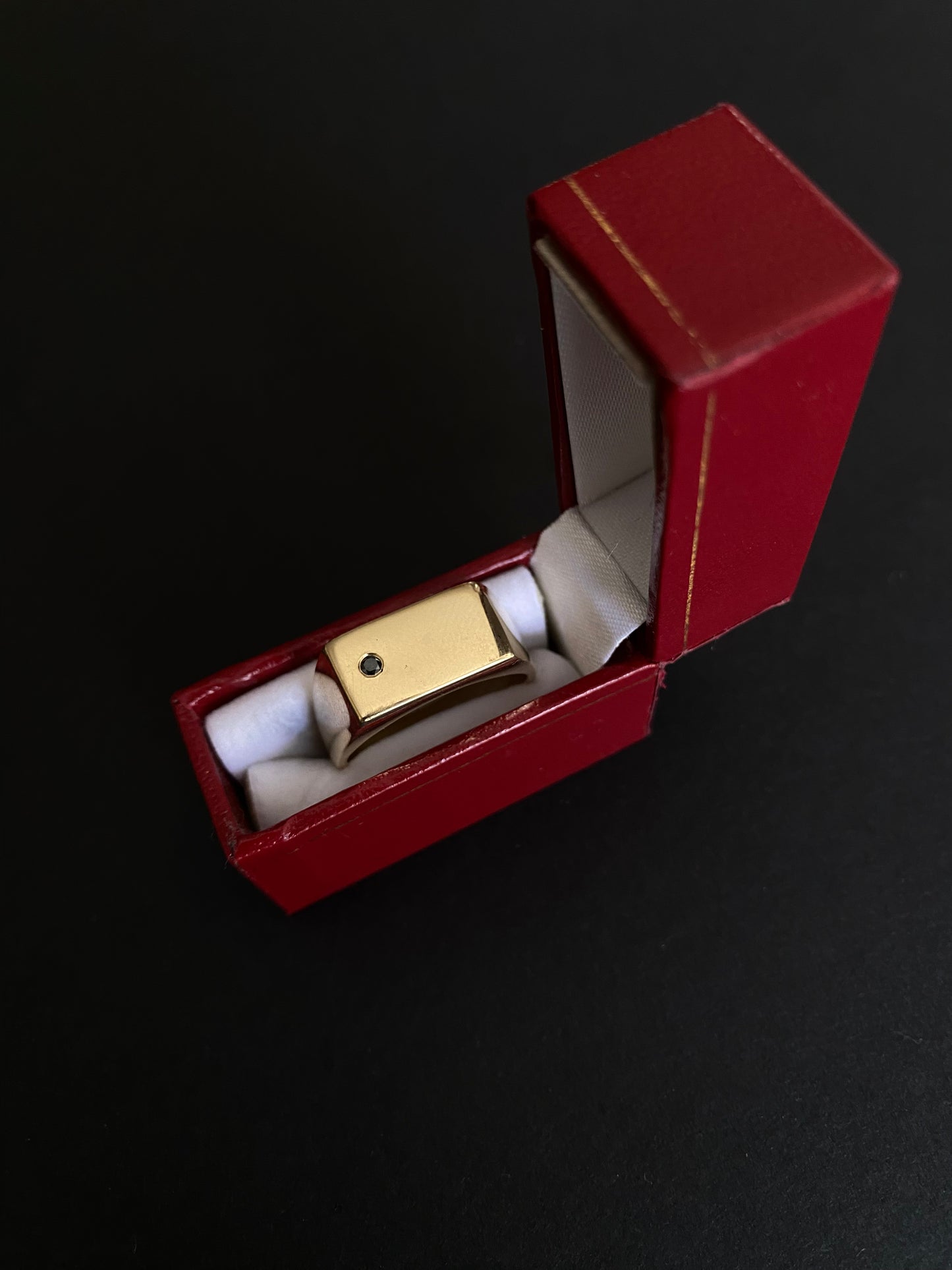 Gold ring with a black gemstone in a red jewelry box on a dark background