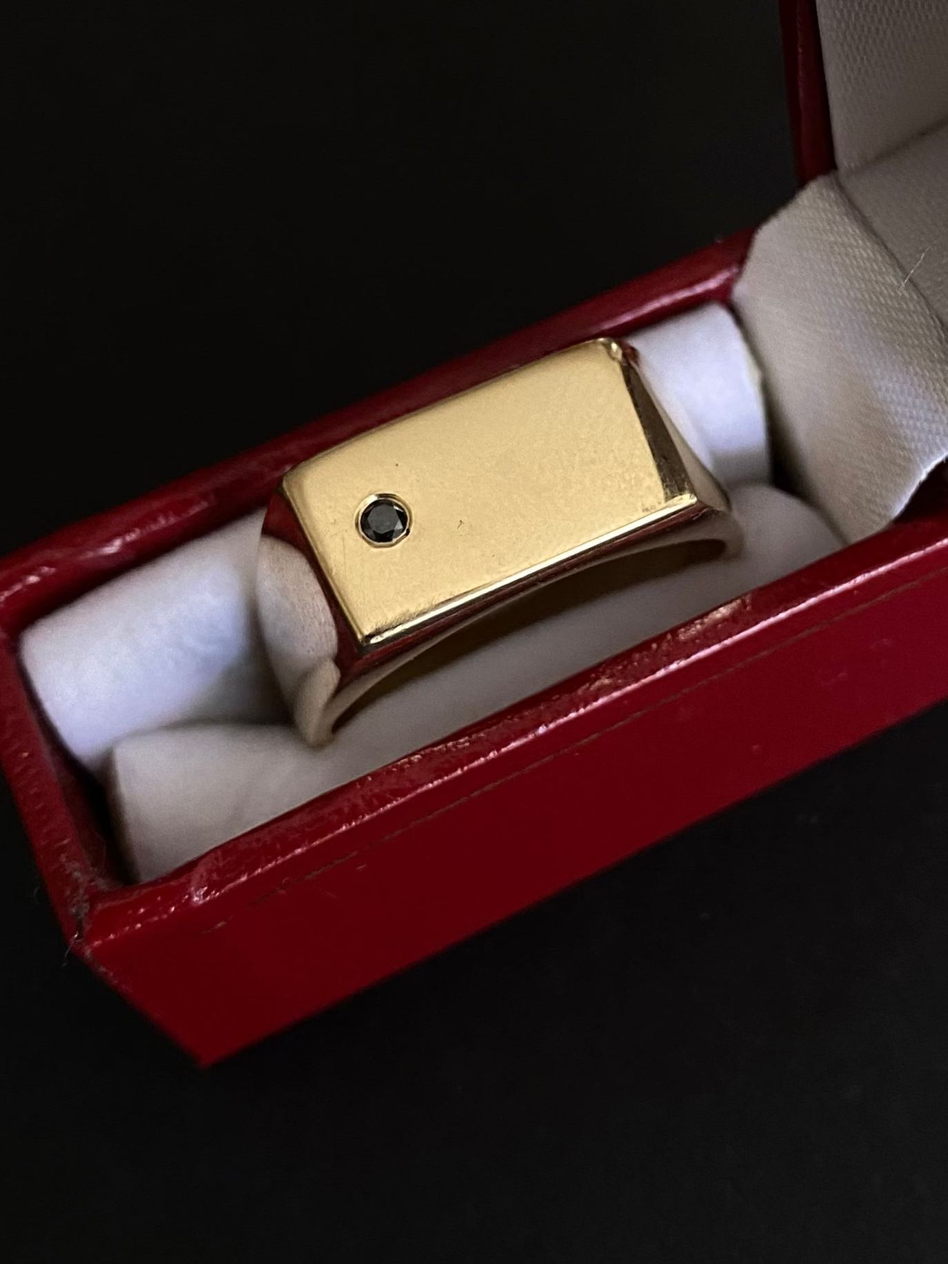 Gold ring with a black gemstone in a red jewelry box on a dark background