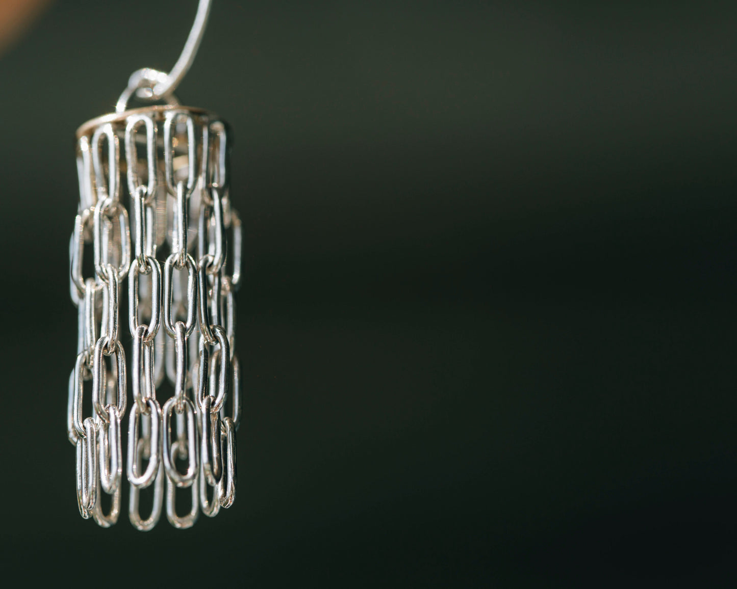 Silver and gold chandelier like earrings against a blurred grey background