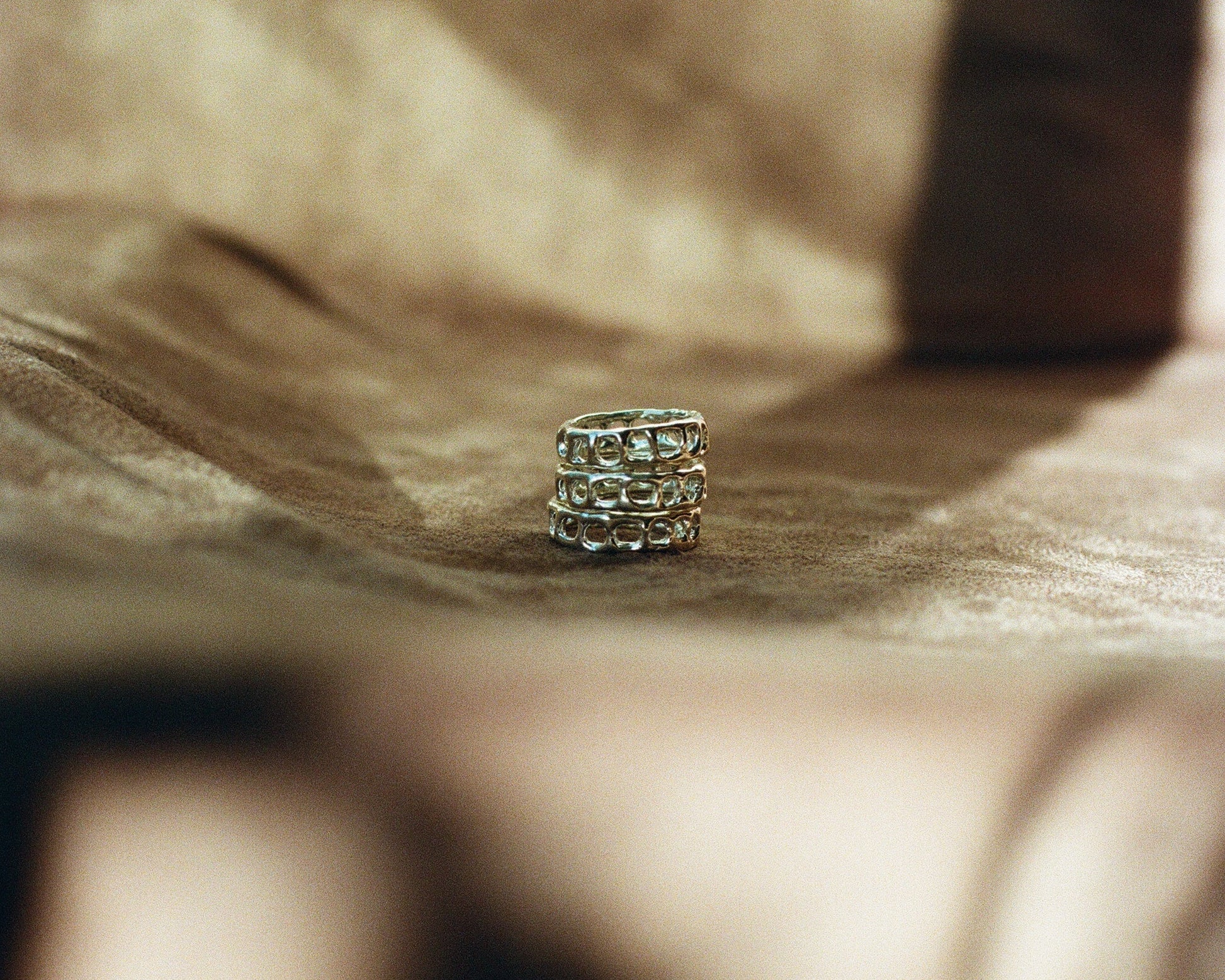 Close up of three stacked silver rings on a brown blurred background