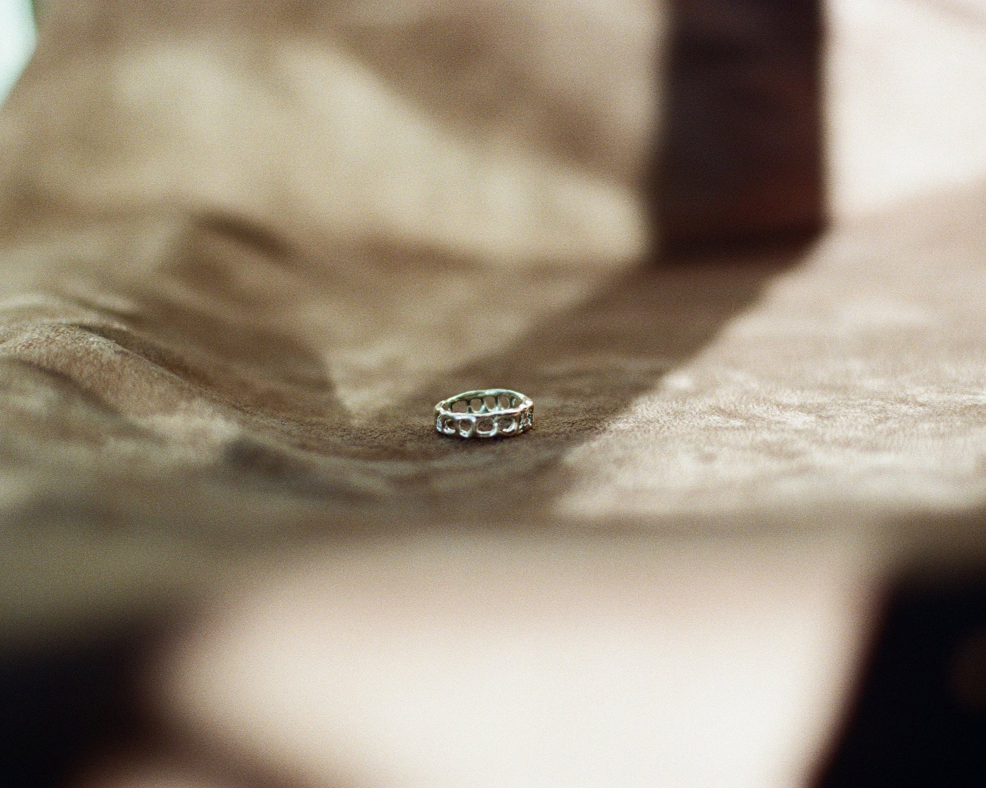 Silver ring on a textured surface with a blurred background