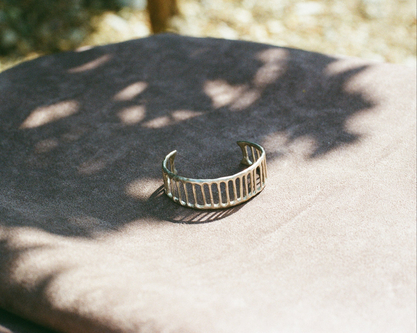Silver bracelet on a textured surface with natural light and shadows