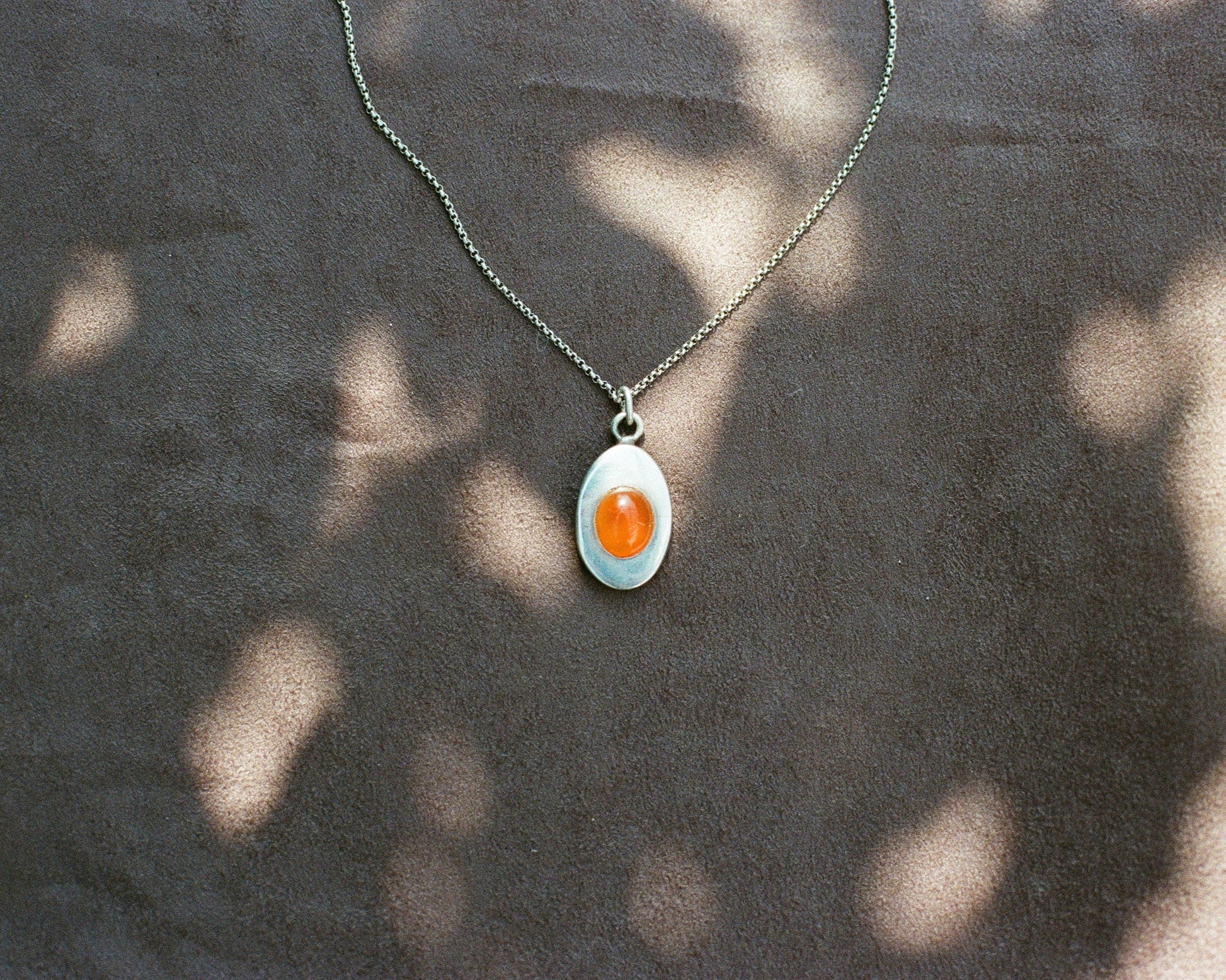 Pendant necklace with a carnelian stone on a blurred background