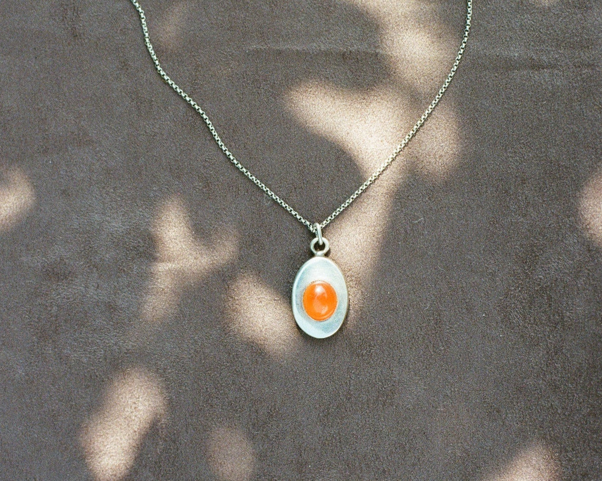 Pendant necklace with a carnelian stone on a blurred background
