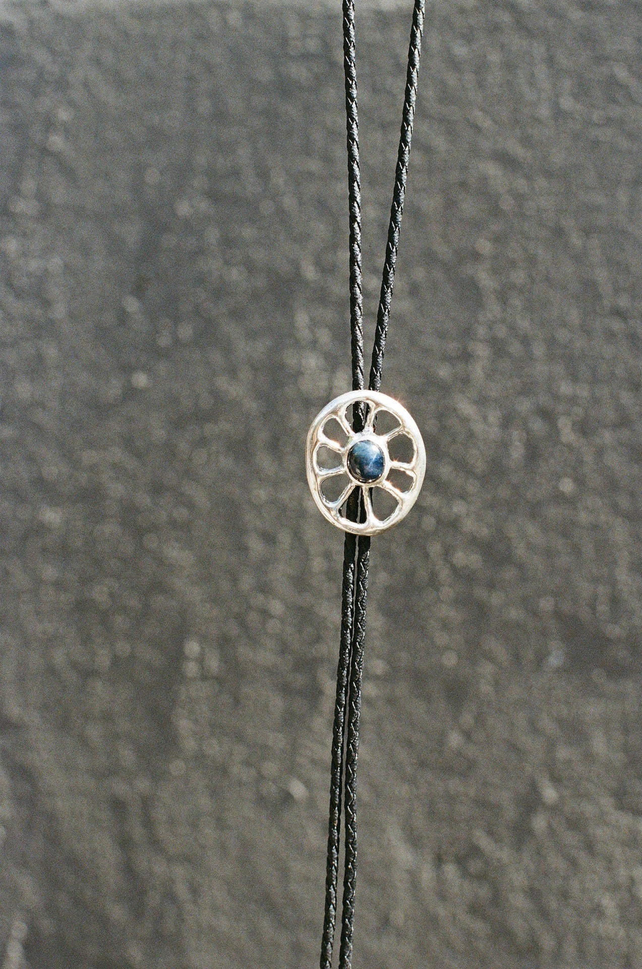 Bolo tie featuring a blue star sapphire against a textured surface