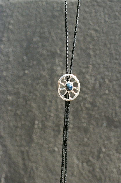 Bolo tie featuring a blue star sapphire against a textured surface