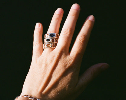 Hand wearing three rings with a dark background