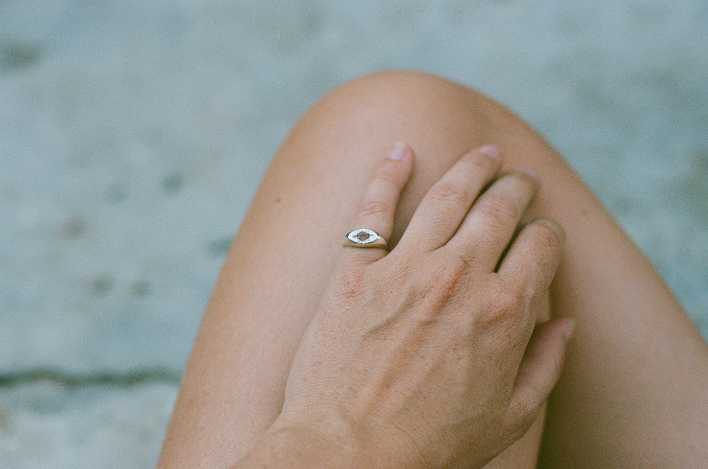 Hand with a ring on a blurred natural background