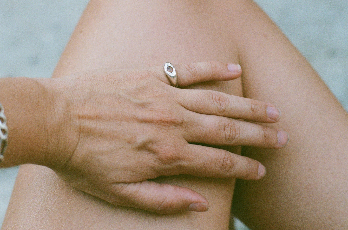 Close-up of a hand with a ring on a knee against a blurred background