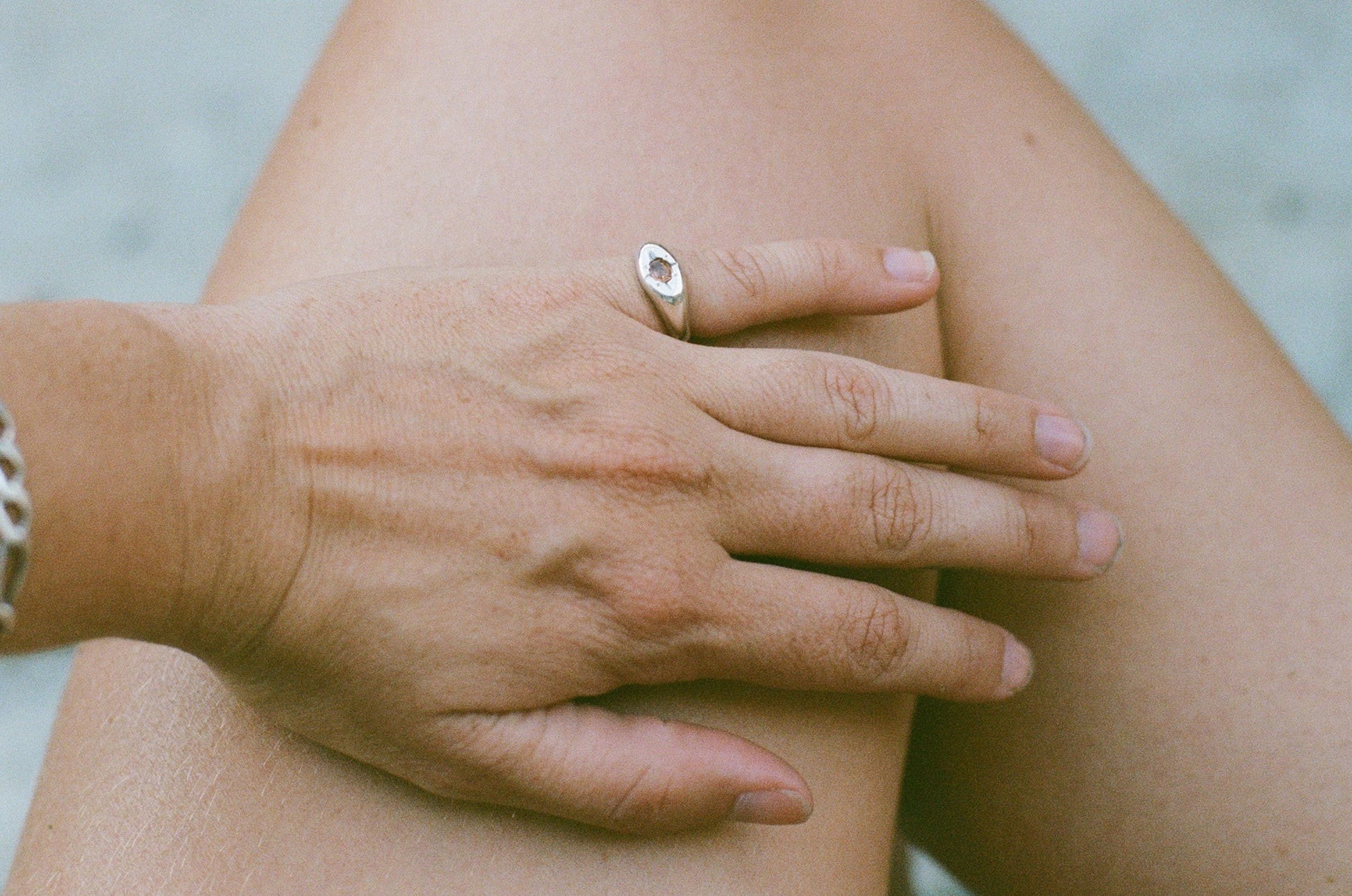 Close-up of a hand with a ring on a knee against a blurred background