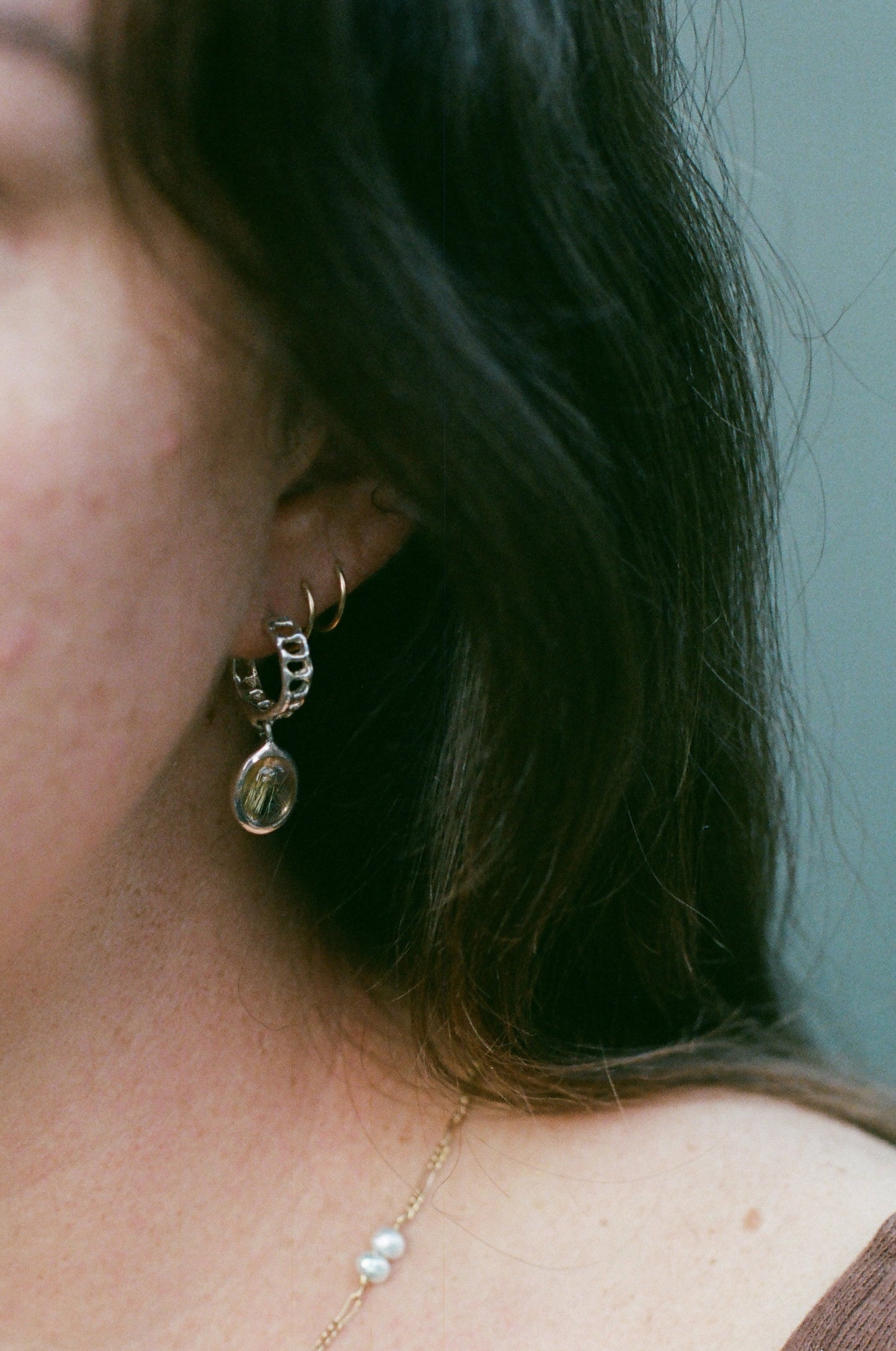 Close-up of a person wearing gold earrings and a delicate necklace.