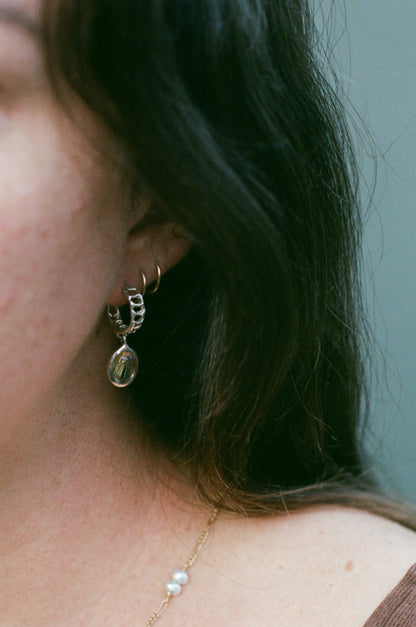 Close-up of a person wearing gold earrings and a delicate necklace.