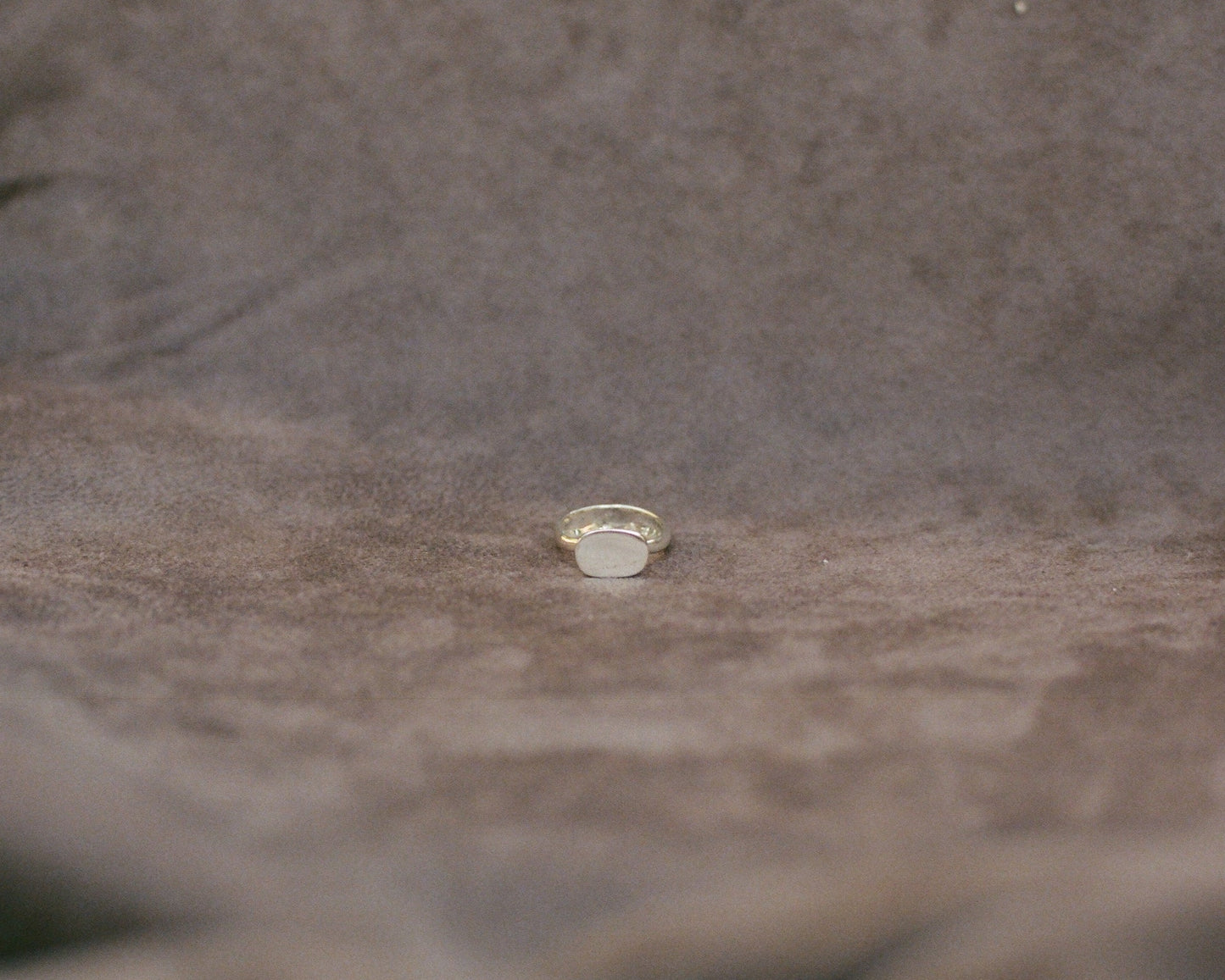 Silver ring on a textured brown fabric surface