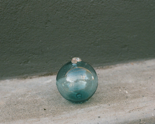 Silver ring on a green glass sphere on a concrete surface with a dark green wall in the background