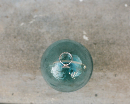 Silver ring on top of a green glass sphere on a concrete surface