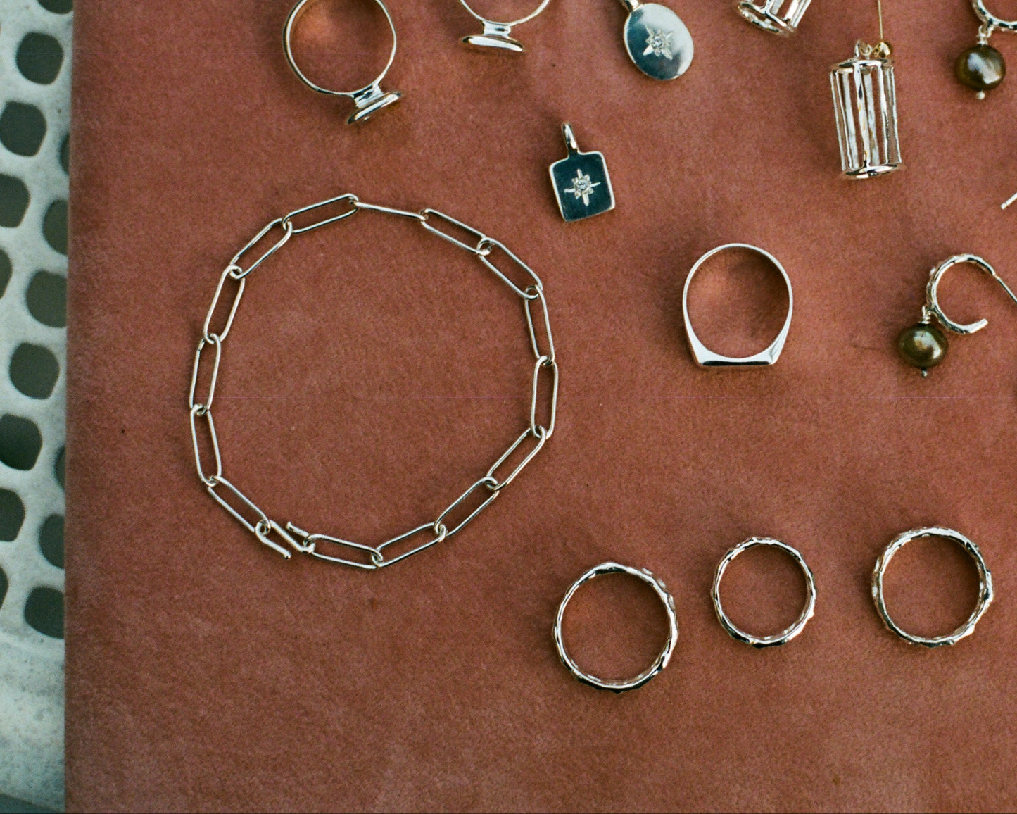 Collection of jewelry including rings, necklaces, and pendants on a textured surface.