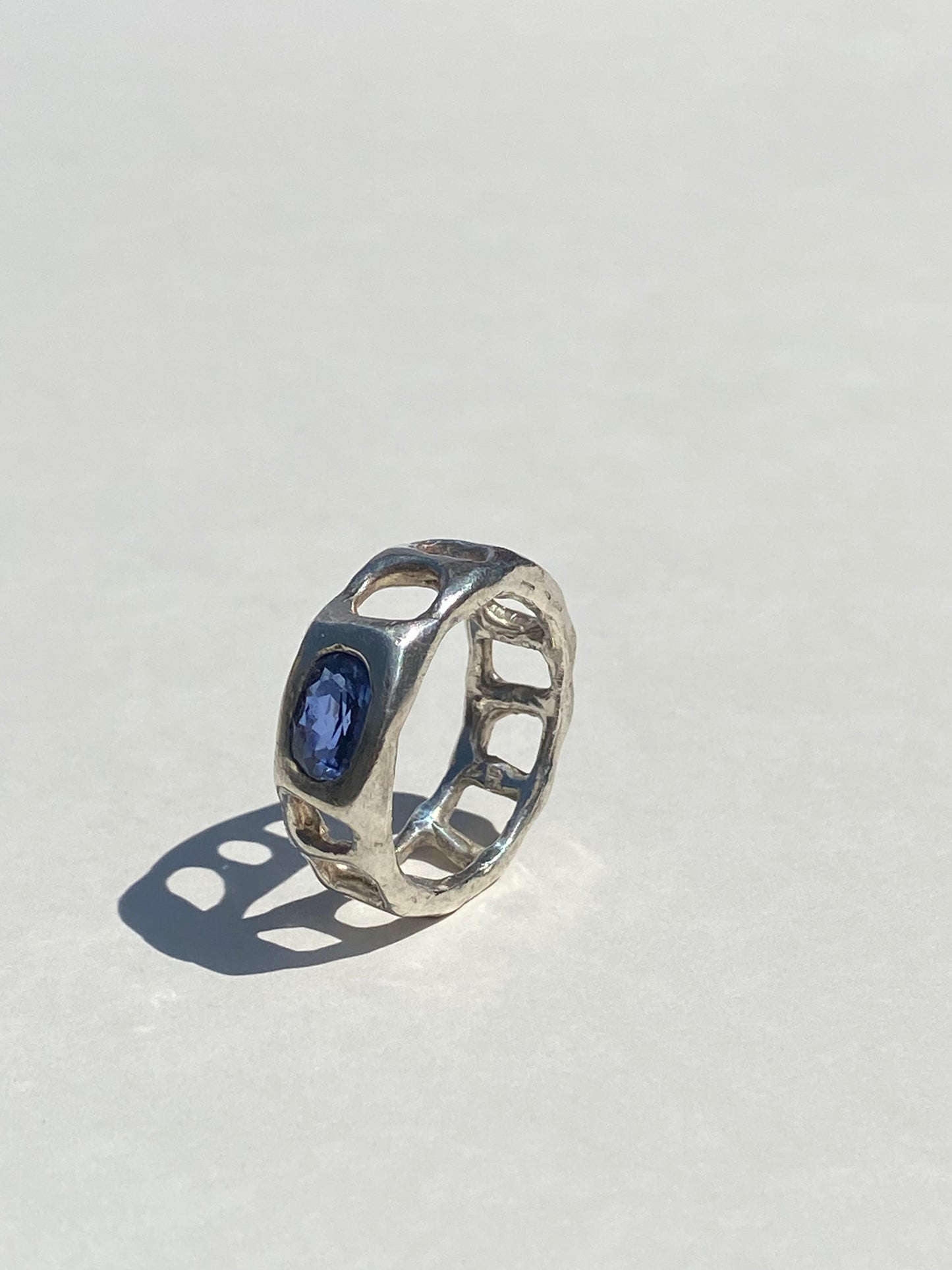 Silver ring with a blue gemstone on a light gray background
