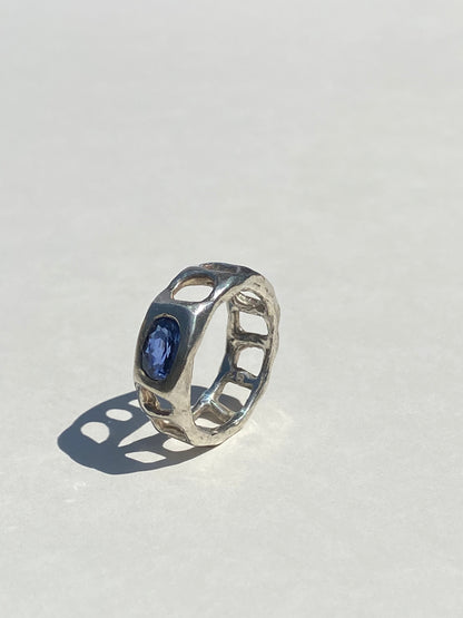 Silver ring with a blue gemstone on a light gray background