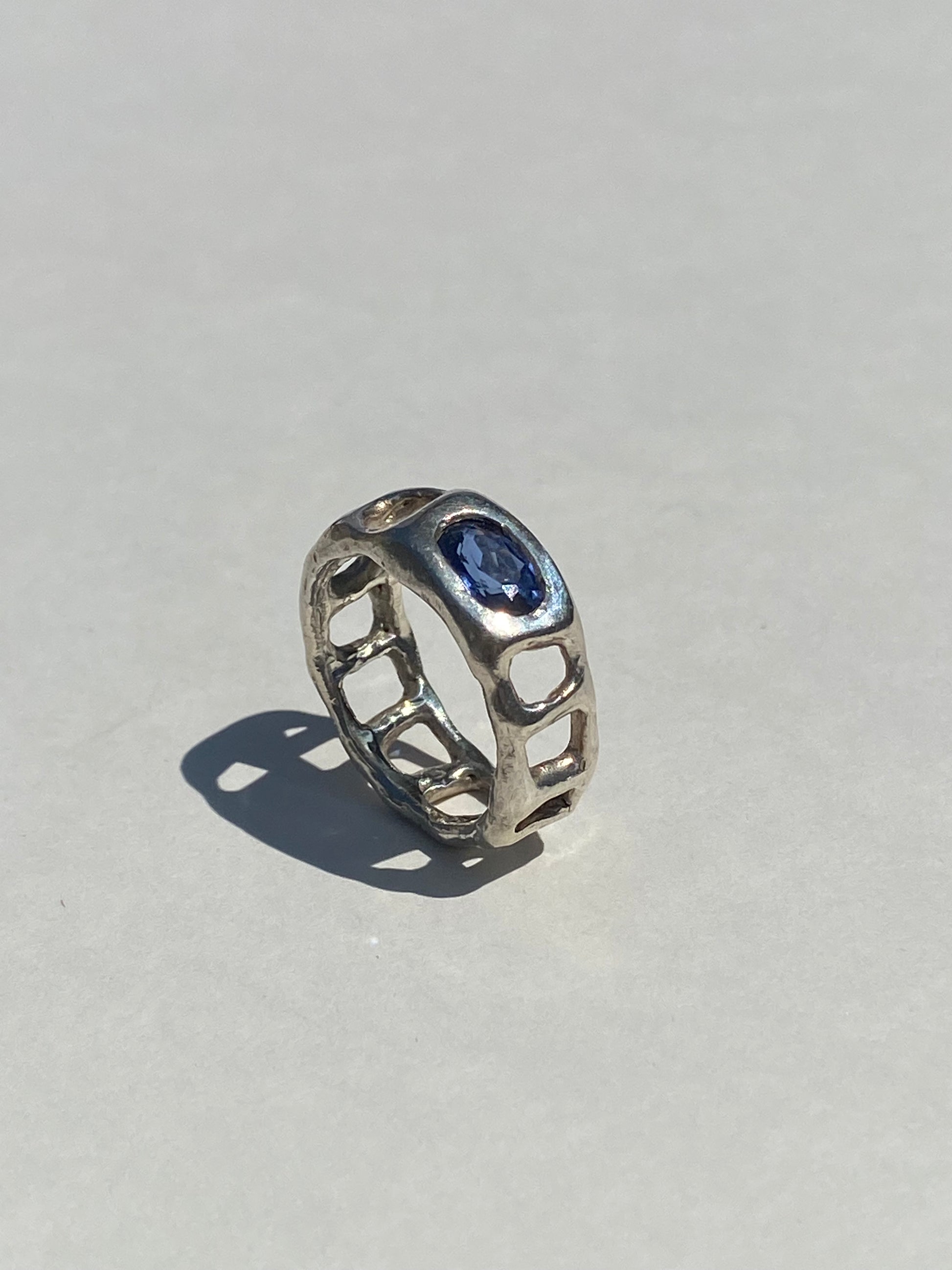 Silver ring with a blue gemstone on a light gray background
