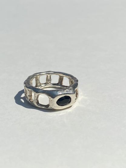 Silver ring with a black stone on a light gray background