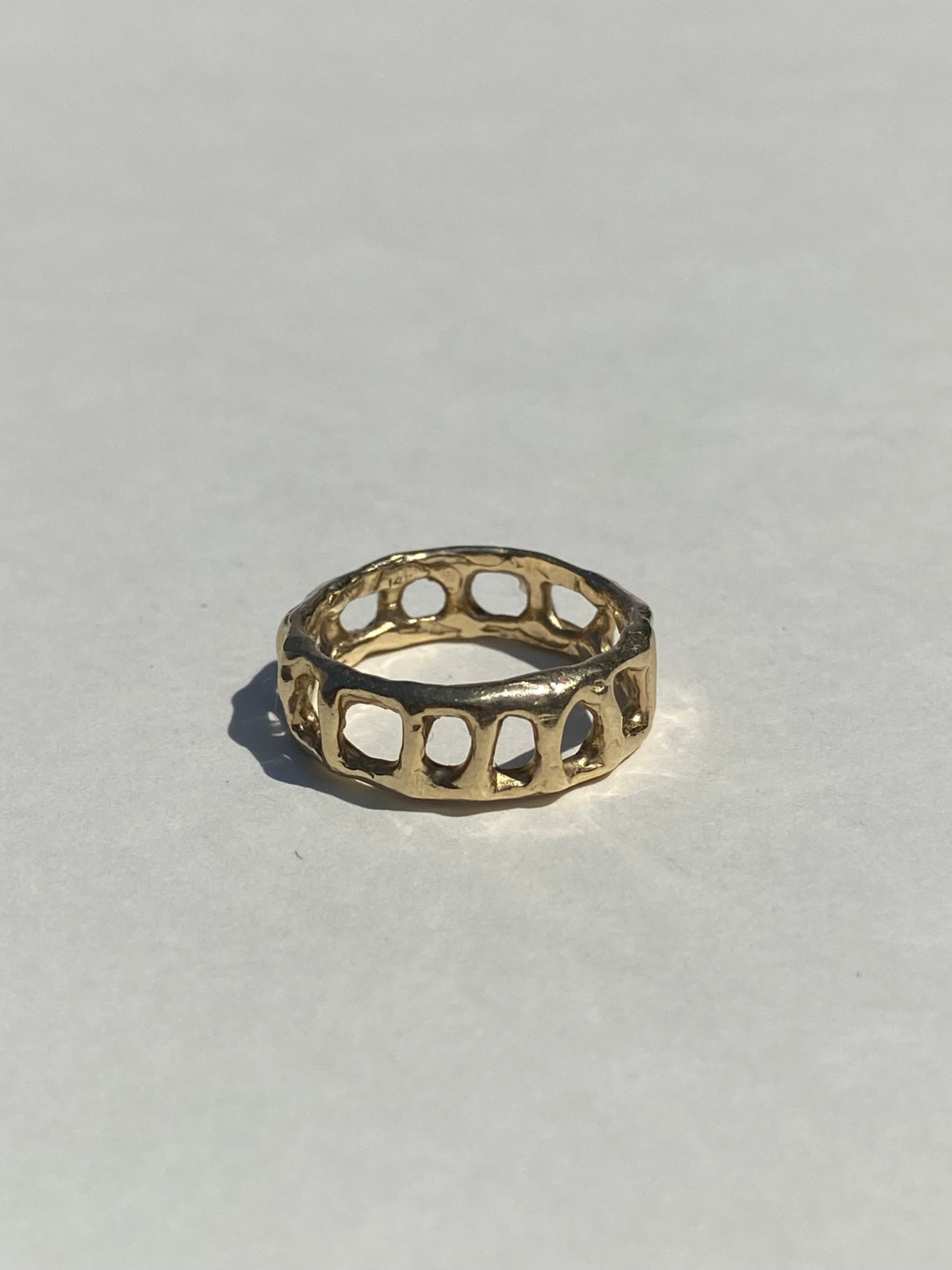 Gold ring with a unique design on a light gray background