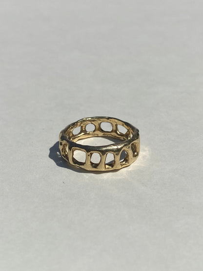 Gold ring with a unique design on a light gray background
