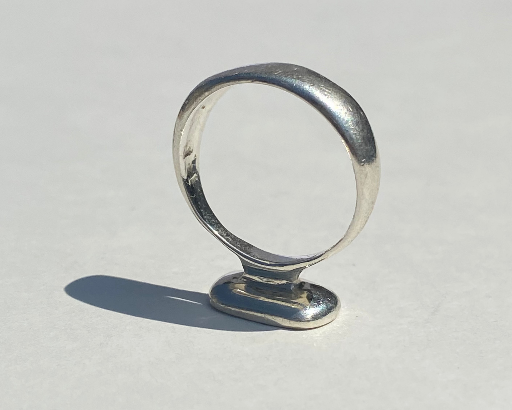 Silver ring on a light gray surface with a neutral background