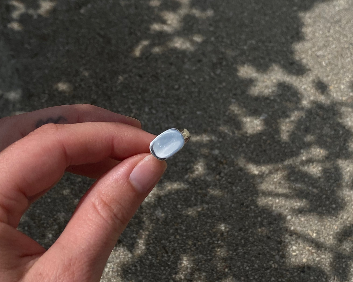 Hand holding a small silver ring against a textured surface