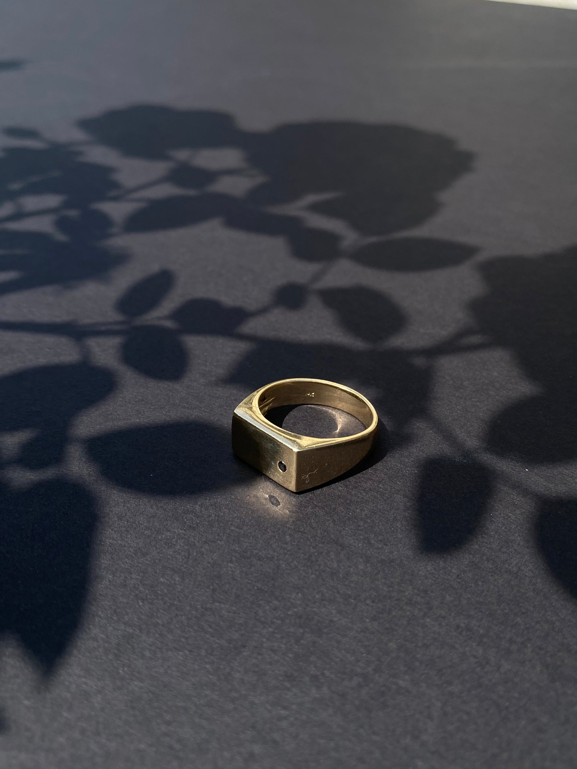Gold ring on a dark surface with leaf shadows