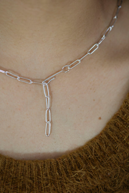 Silver chain necklace on a person's neck with a blurred background