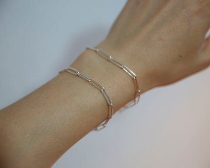 Silver bracelet on a wrist against a neutral background