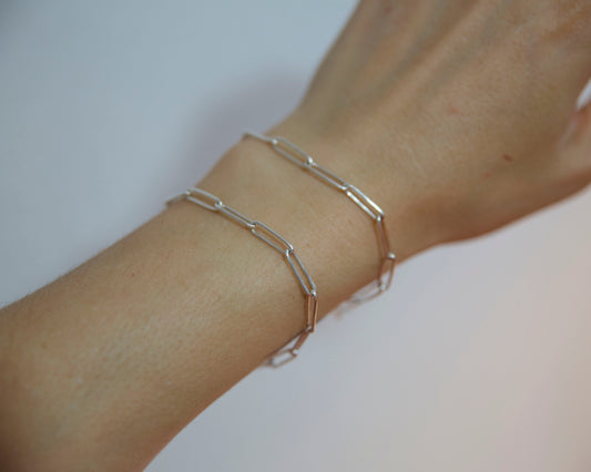 Silver bracelet on a wrist against a neutral background
