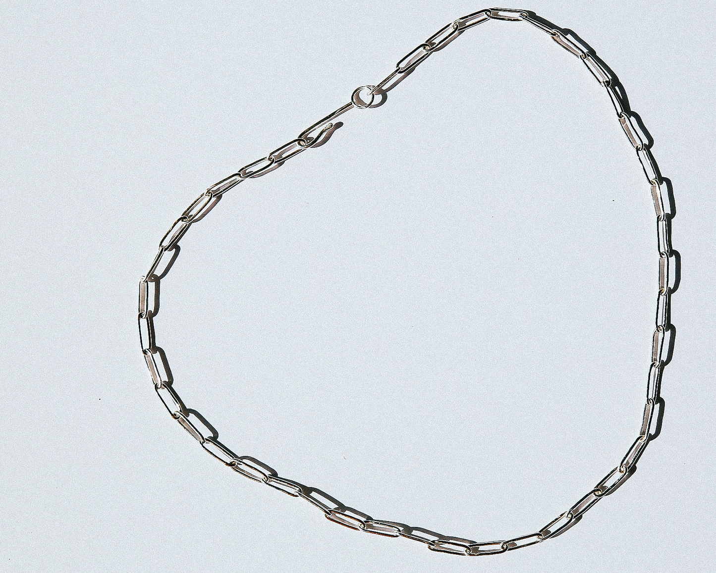 Silver chain necklace on a light gray background