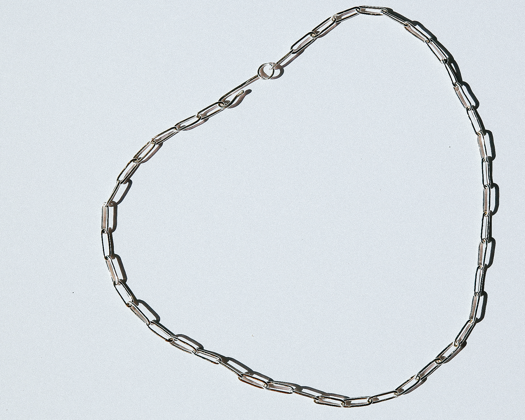 Silver chain necklace on a light gray background